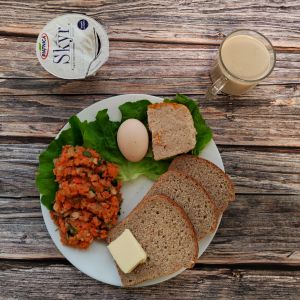 Zdjęcie przedstawia Dietę z ograniczeniem łatwoprzyswajalnych węglowodanów: Masło extra Pasztet drobiowy z kurnej półki Pasta warzywna Kawa zbożowa z mlekiem Chleb Graham Jogurt typu islandzkiego naturalny Skyr Woda mineralna Sałata zielona Jajko gotowane